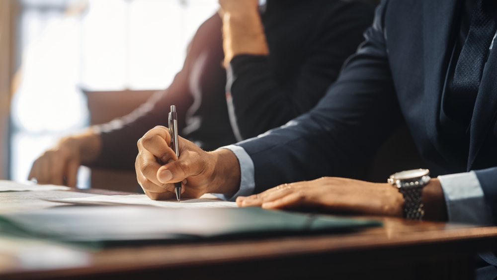 Photo of a person at the table writing on the paper