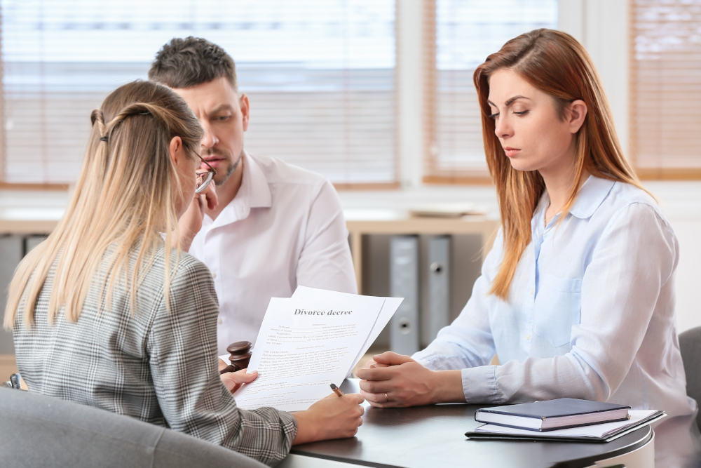 Divorce Settlement Meeting Three professionals in an office reviewing documents on the table