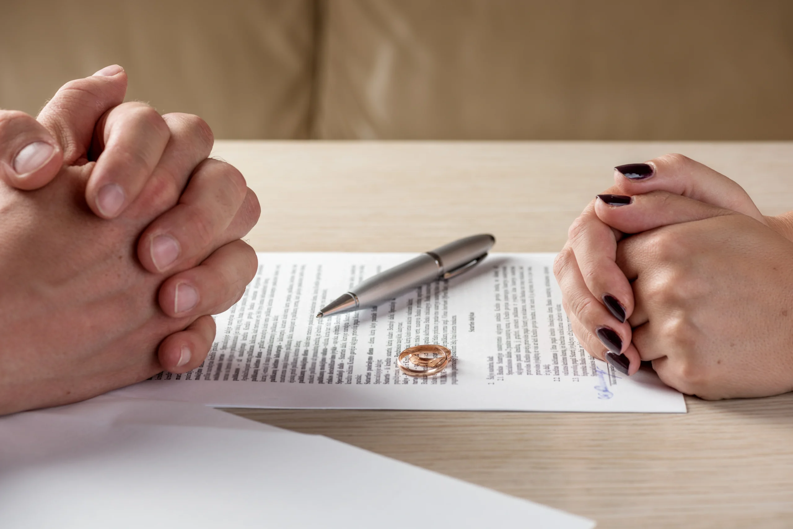 Woman Taking off Her Ring stressed couple sits at a table with legal papers between them, representing the difficult process of a contested divorce