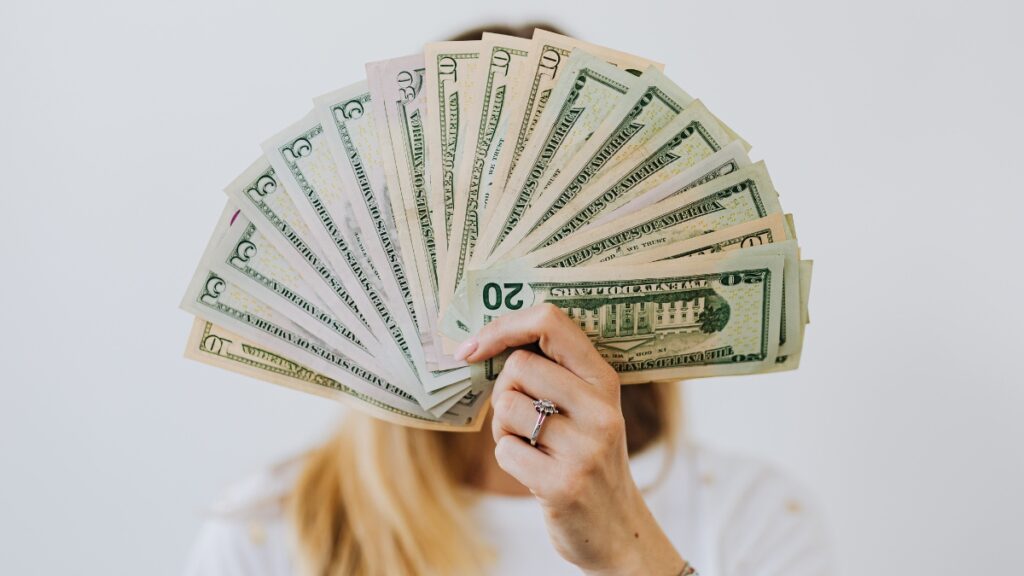 woman with stack of money fanned out in front of her face